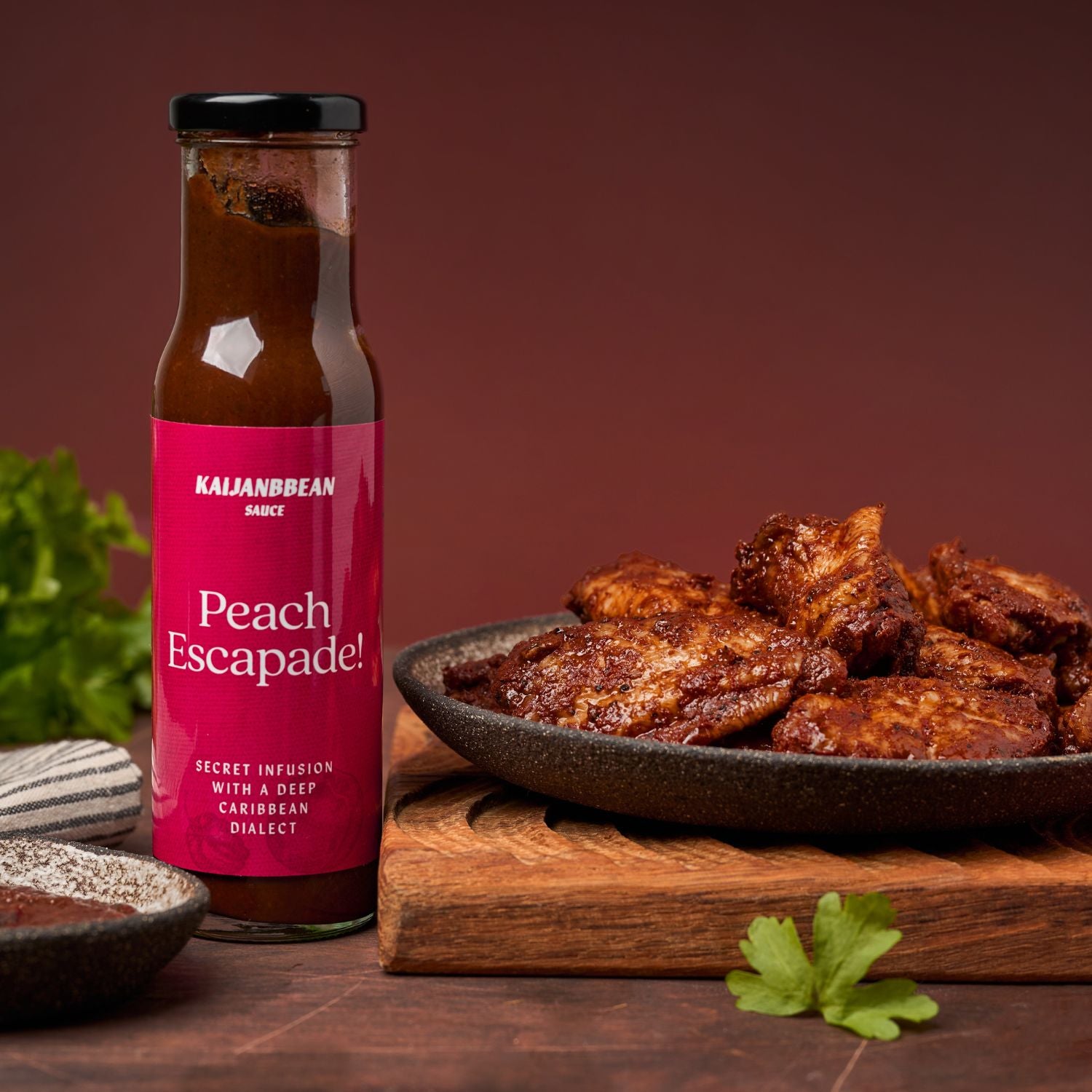 Bottle of Kajani & Bean Peach Escapade sauce with fried food on a wooden board